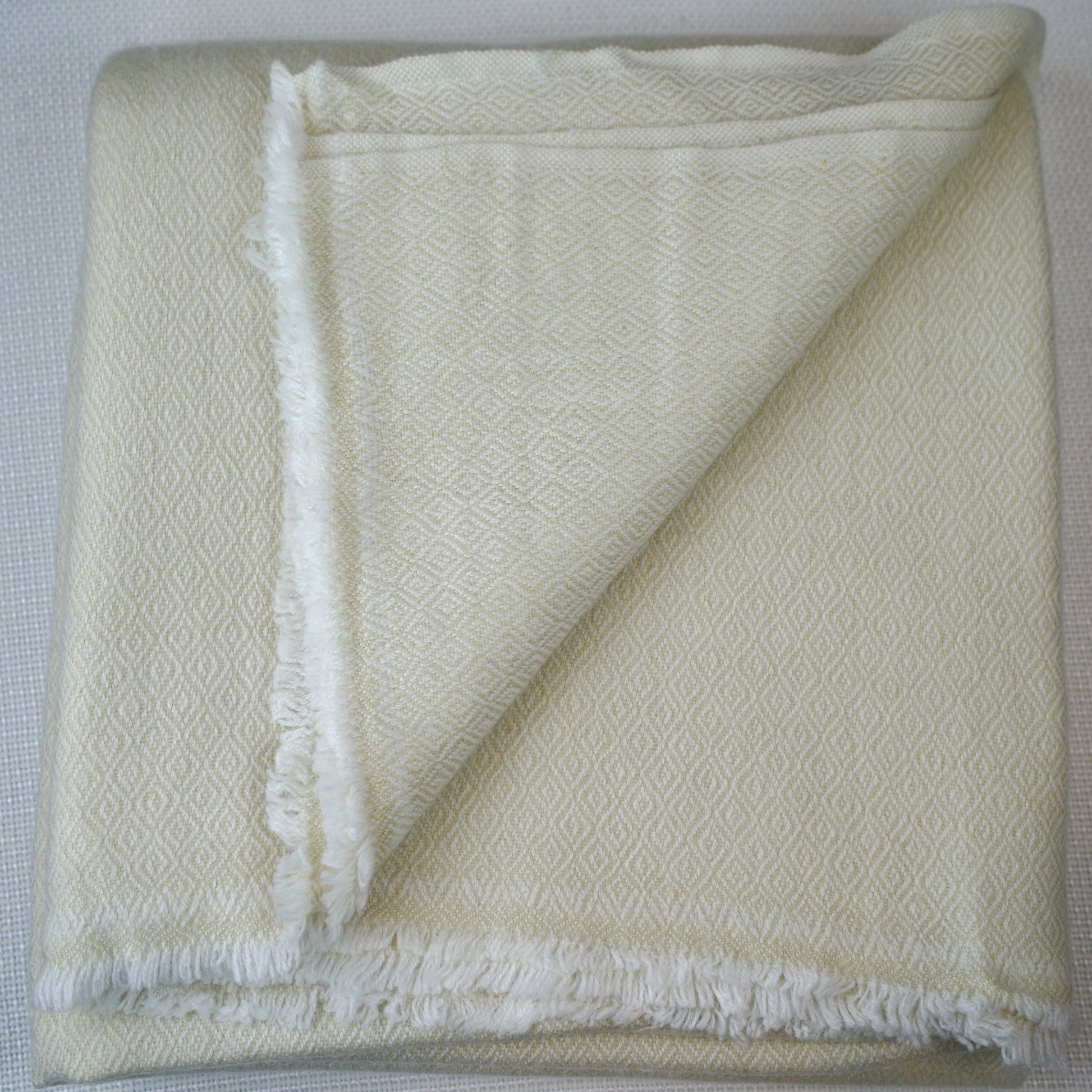Folded white textured blanket on a light gray background