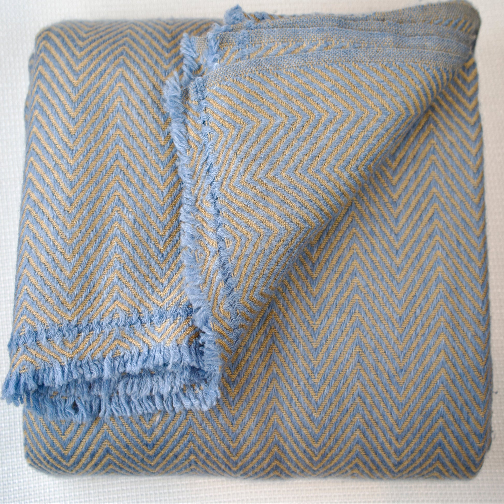 Folded blue and golden patterned blanket on a white background