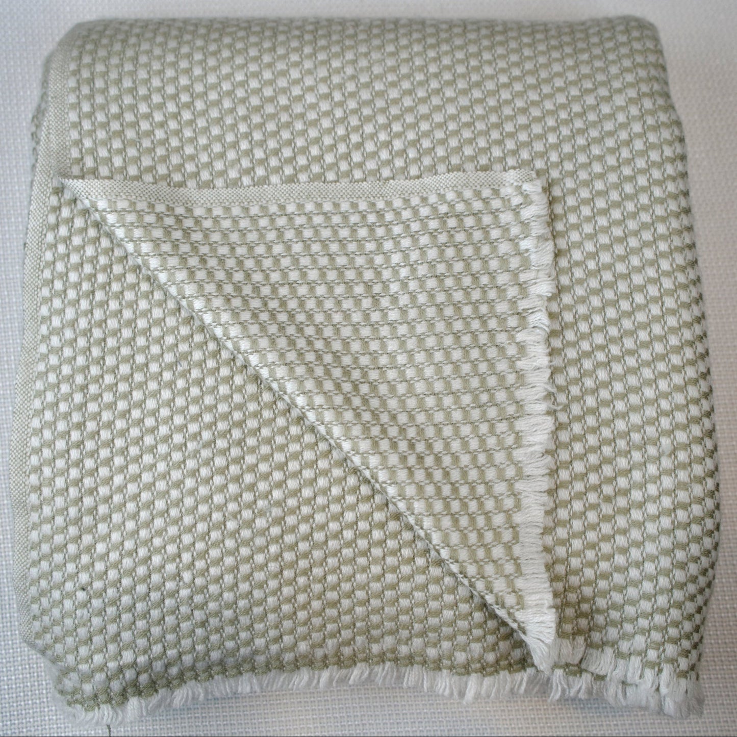 Light grey textured blanket with a geometric pattern on a light background